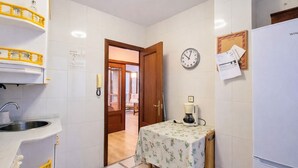 Cocina compacta con un lavabo, una cafetera y un reloj en la pared.