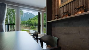 A modern dining area with a long wooden table, chairs, and a view of a mountain landscape through large windows. - CONTRAIL【Ezo Fuji hoothills】 (Makkari-mura)