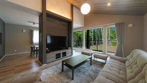A modern living room with a large flat-screen TV, a dark coffee table, and a plush sofa. - CONTRAIL【Ezo Fuji hoothills】 (Makkari-mura)