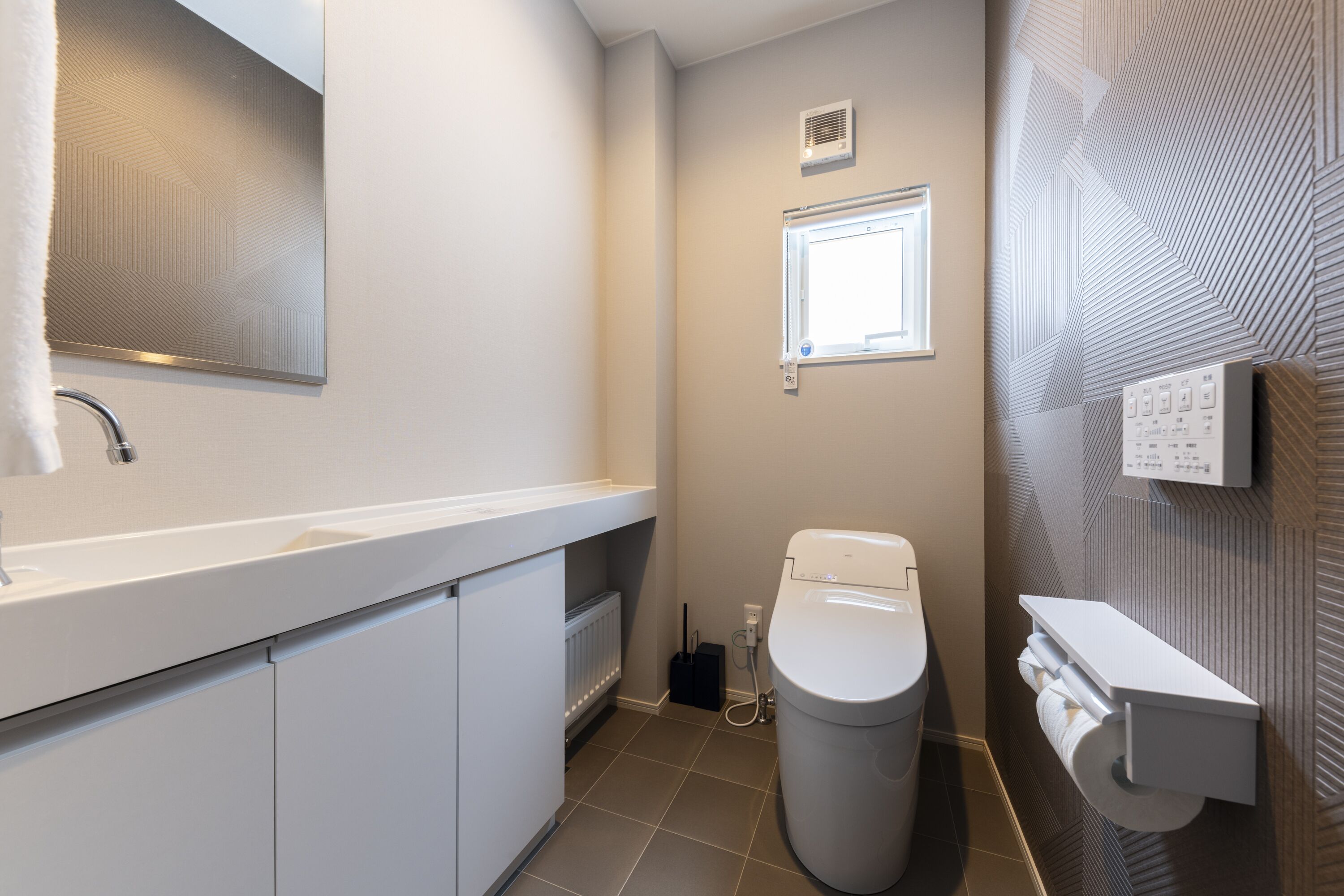 A modern bathroom with a white sink, toilet, and towel rack.