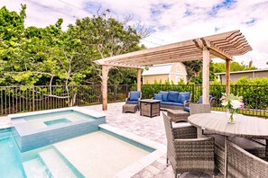 Um quintal com piscina, móveis de exterior e um pérgola.