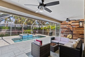 An indoor pool area with a glass ceiling, wicker furniture, and a wooden wall.