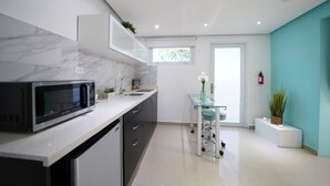 A modern kitchen with a built-in microwave, a sink, and a glass dining table.