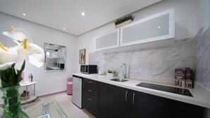 A modern kitchen with dark cabinets, a white countertop, and a built-in microwave.