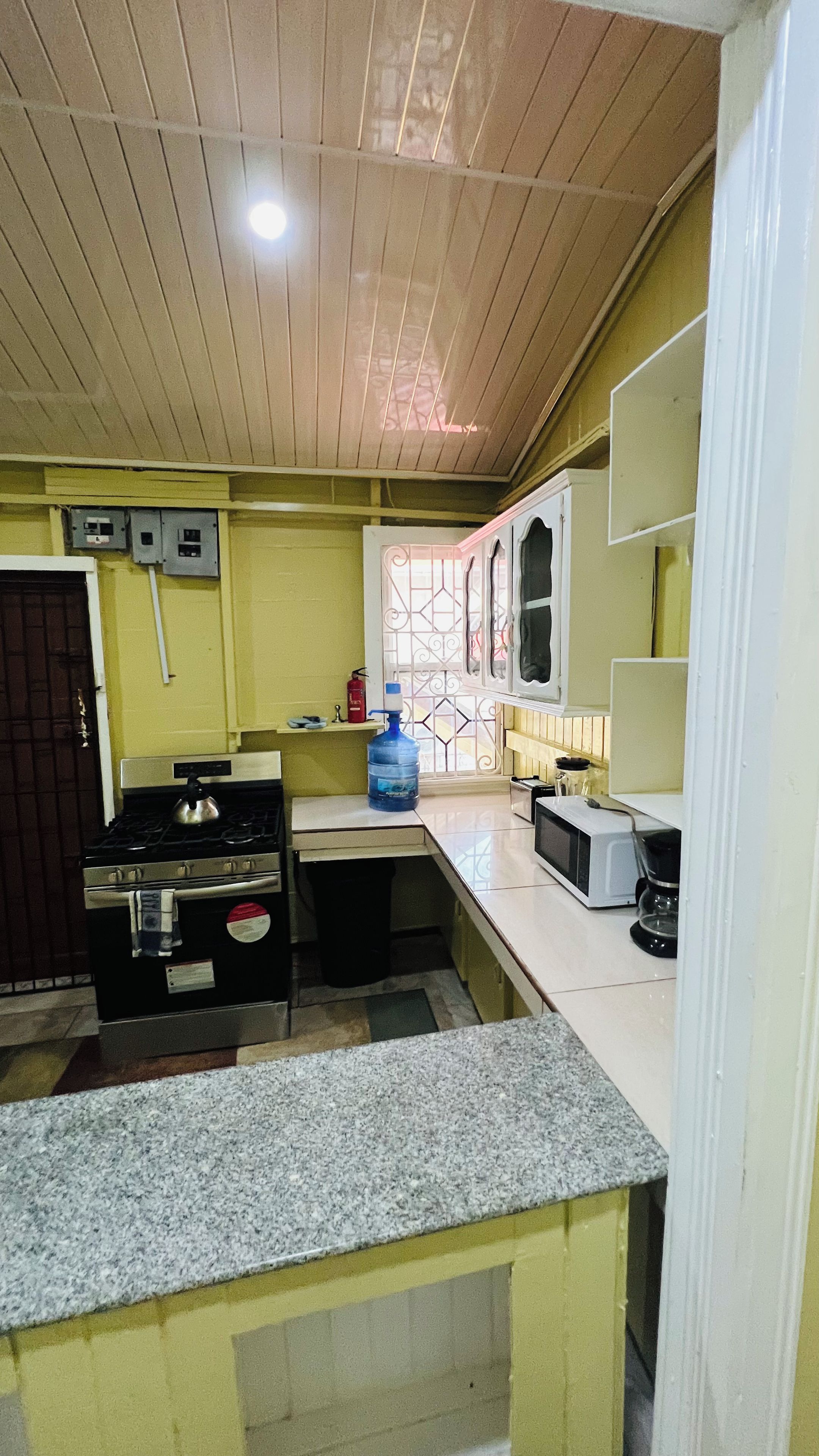 Una cocina compacta con estufa a gas, microondas y dispensador de agua.