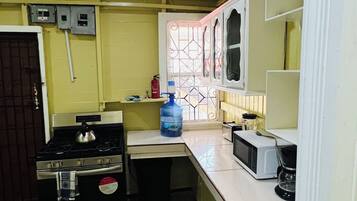 Una cocina compacta con estufa a gas, microondas y dispensador de agua.