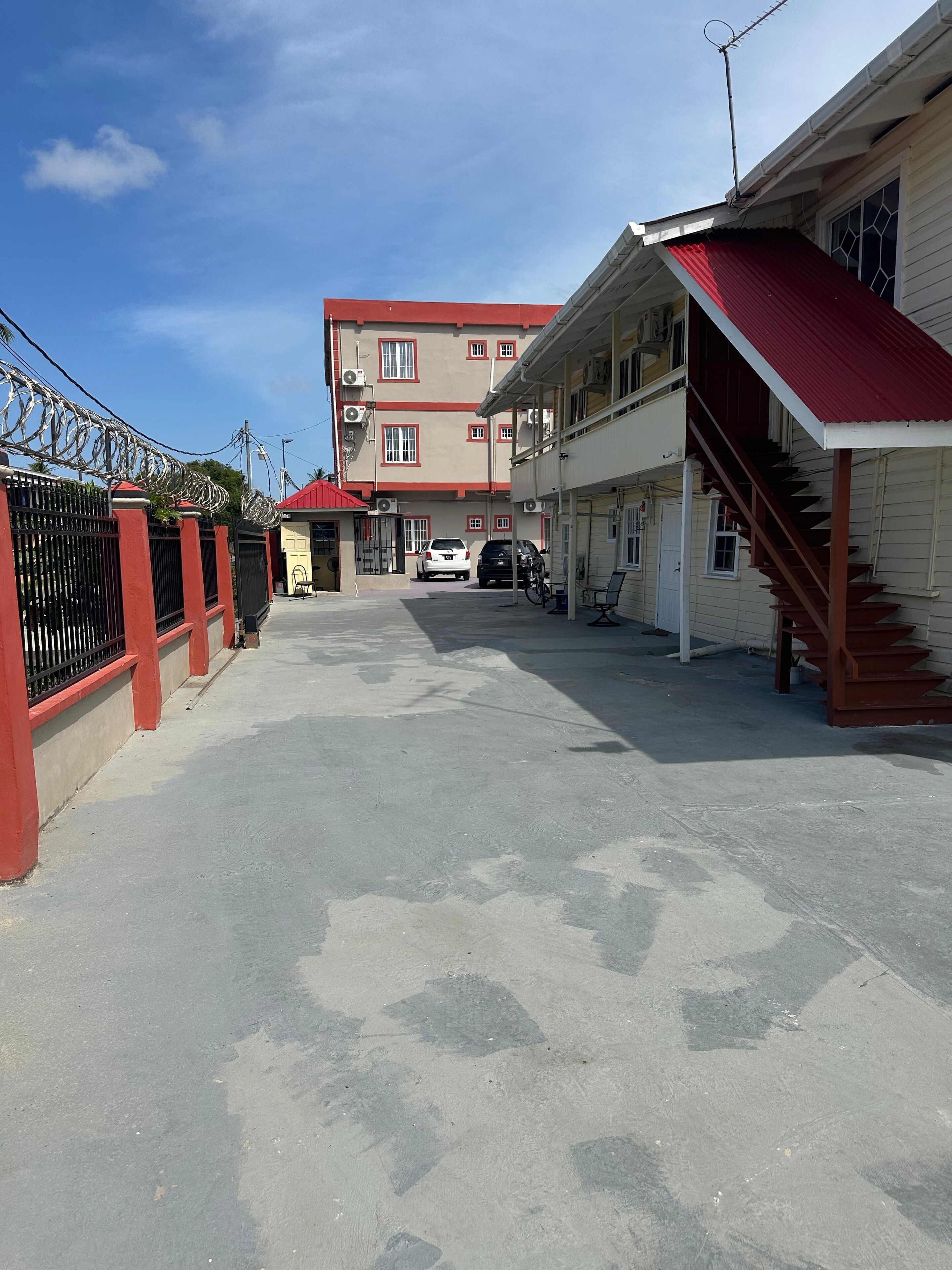 Un bâtiment avec un toit rouge, un escalier et une voiture garée devant.