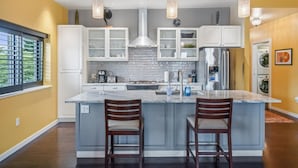 Een moderne keuken met een centraal eiland, witte kasten en hanglampen.