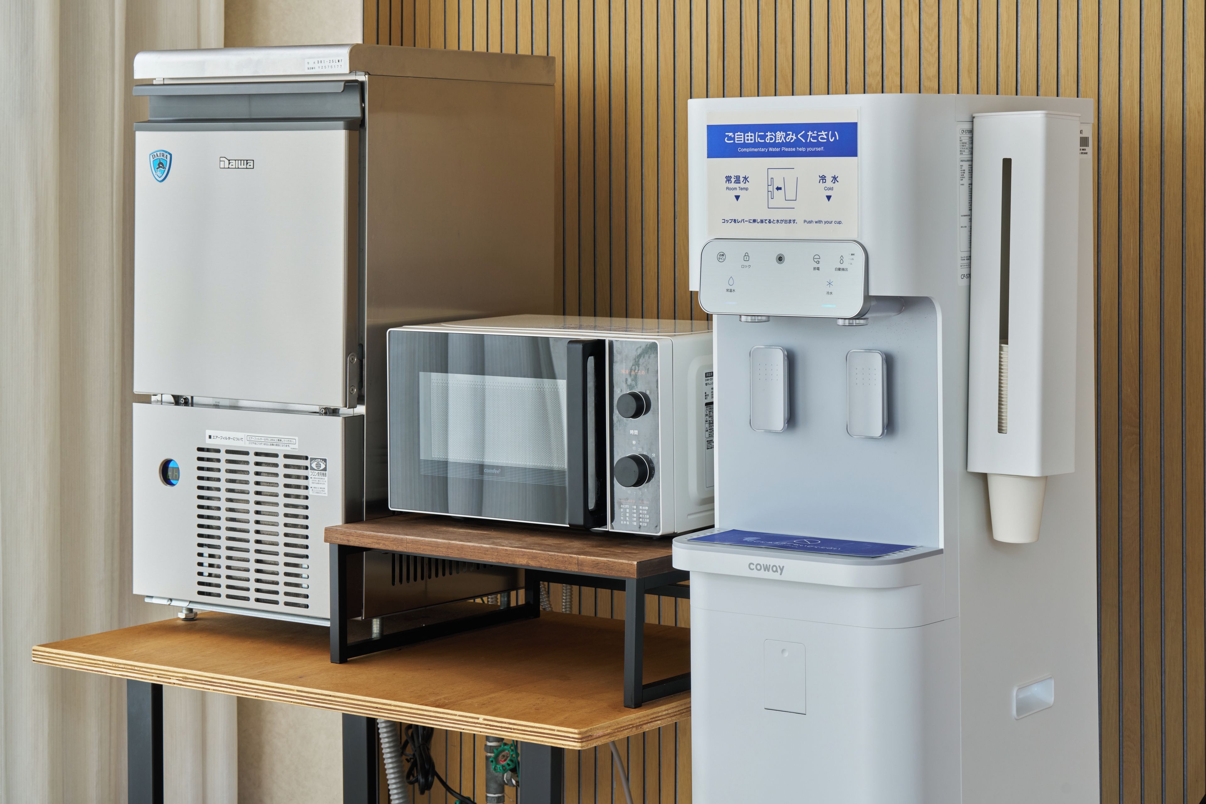 A kitchenette with a refrigerator, microwave, and coffee machine.