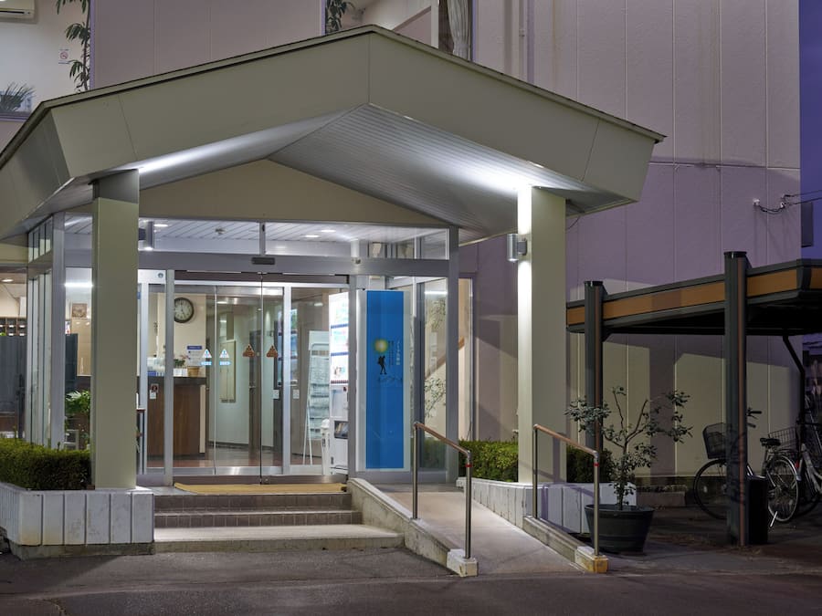 A hotel entrance with a covered entrance, glass doors, a clock, and a blue door.