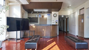 A reception area with a wooden counter, a bench, and a potted plant. - Hotel Noble Iiyama (Iiyama)