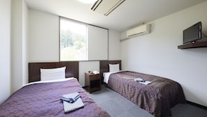 A hotel room with two beds, a TV on a stand, an air conditioner, and a window with a view of trees. - Hotel Noble Iiyama (Iiyama)