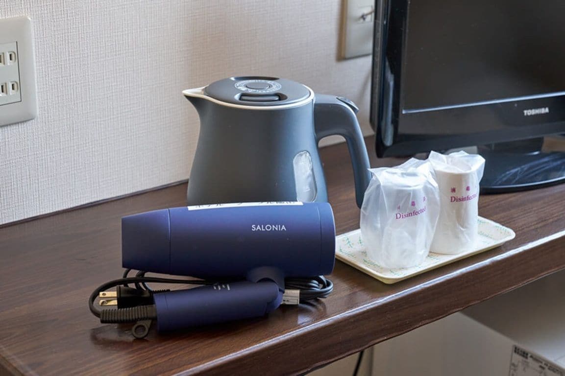 A desk with a kettle, a blue device, and two disinfectant bags.