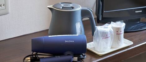 A desk with a kettle, a blue device, and two disinfectant bags.
