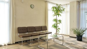 A waiting area with a sofa, a glass table, and potted plants. - Hotel Noble Iiyama (Iiyama)