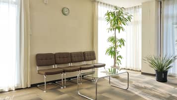 Un área de espera con un sofá, una mesa de vidrio y plantas en macetas.