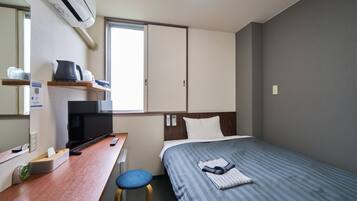 Una habitación de hotel con cama, escritorio, silla, televisor y ventana.