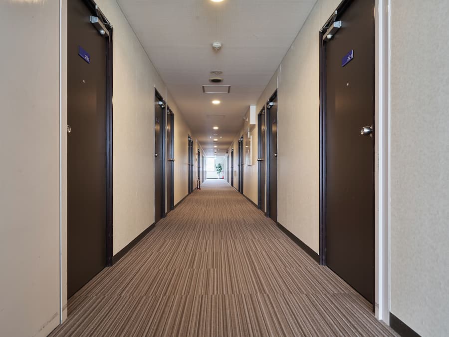 Un pasillo de hotel con puertas numeradas 201 y 221, piso alfombrado e iluminación empotrada.