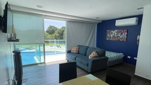 Uma sala de estar moderna com sofá, mesa de jantar e vista para uma piscina.