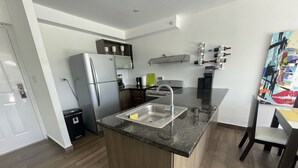 Uma cozinha moderna com geladeira de aço inoxidável, micro-ondas embutido e fogão a gás.