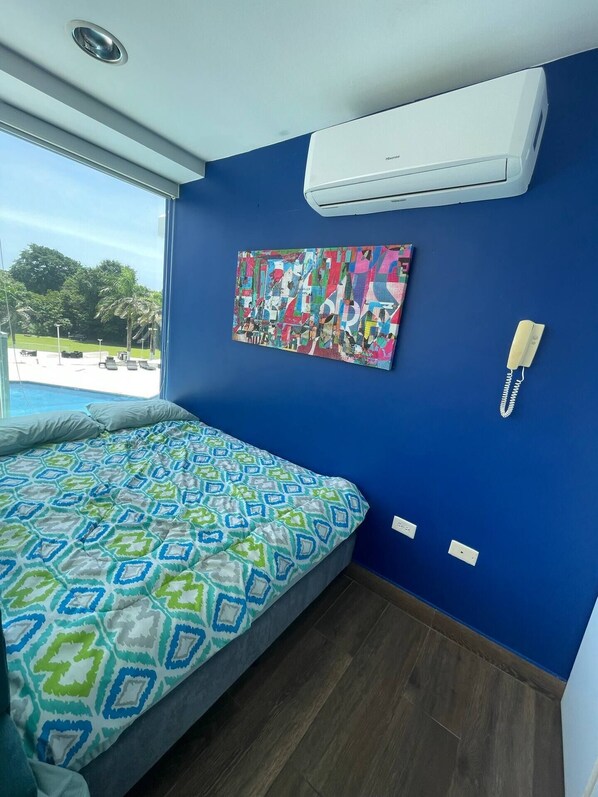 Quarto com cama, um quadro abstrato colorido, telefone e ar condicionado.