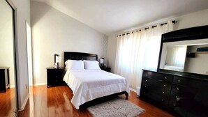 Un dormitorio con cama, mesitas de noche, cómoda y espejo.