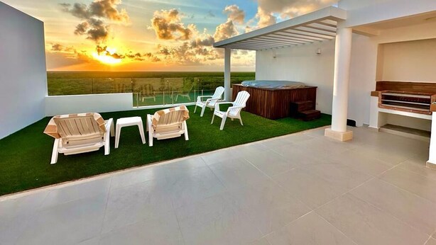 A rooftop terrace with a view of the sunset, a hot tub, and outdoor seating.