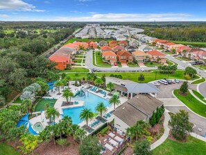 A residential area with a large swimming pool, multiple houses, and a well-maintained lawn. - Large 4-Bedroom 4-Bathroom Pool near attractions and Theme Parks (Kissimmee)