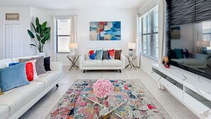 A living room with a white sofa, a coffee table, and a large painting on the wall. - Large 4-Bedroom 4-Bathroom Pool near attractions and Theme Parks (Kissimmee)