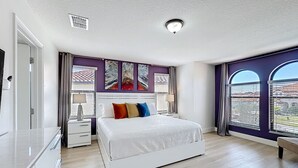 A bedroom with a bed, bedside tables, a window with blinds, and a view of buildings outside. - Large 4-Bedroom 4-Bathroom Pool near attractions and Theme Parks (Kissimmee)
