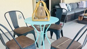 An outdoor seating area with a round table and four chairs, a sofa, and a decorative lantern.