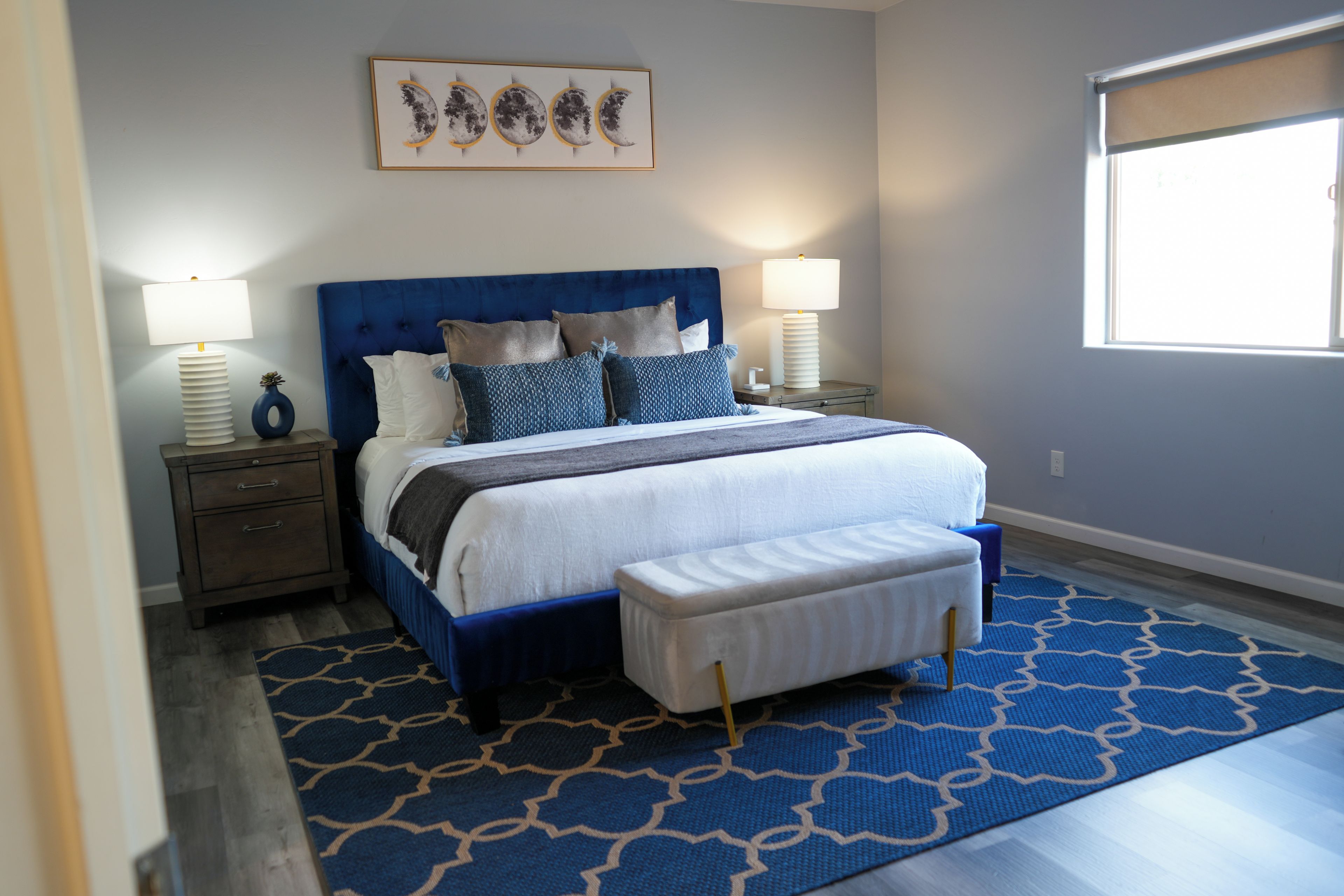 A bedroom with a large bed, two bedside tables, a headboard, and a window.