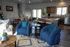 A modern living room with blue armchairs, a coffee table, and a dining area with a table set for four. - Bright Star - Hot Tub • Near Sedona & Old Town (Cottonwood)