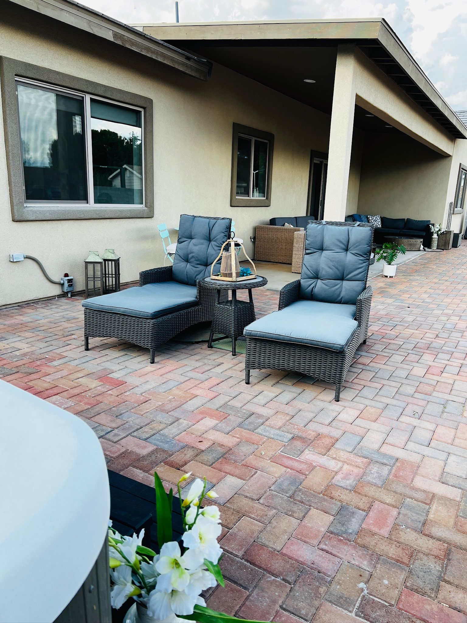 An outdoor patio with wicker furniture, a round table, and a potted plant.