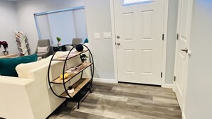 A modern living room with a white sofa, a coffee table, and a bookshelf.