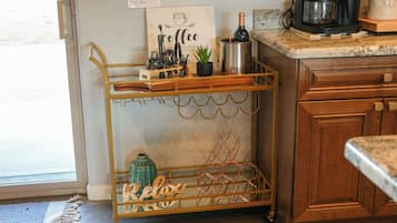 Una cucina con una moka, una bottiglia di vino e un cartello decorativo.
