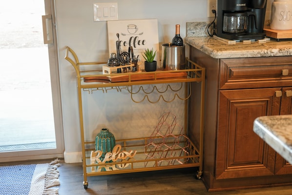 A kitchen with a coffee maker, a wine bottle, and a decorative sign.