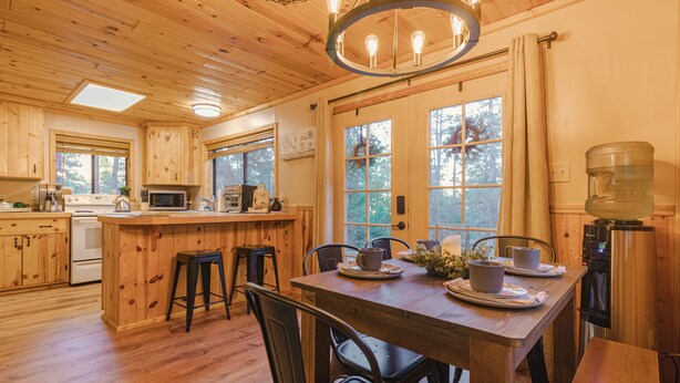 A wooden cabin-style kitchen with a central island, bar stools, and a dining table set for four.