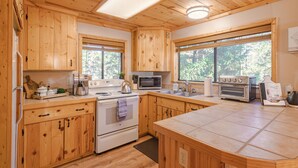 A wooden kitchen with a central island, built-in microwave, oven, and sink.
