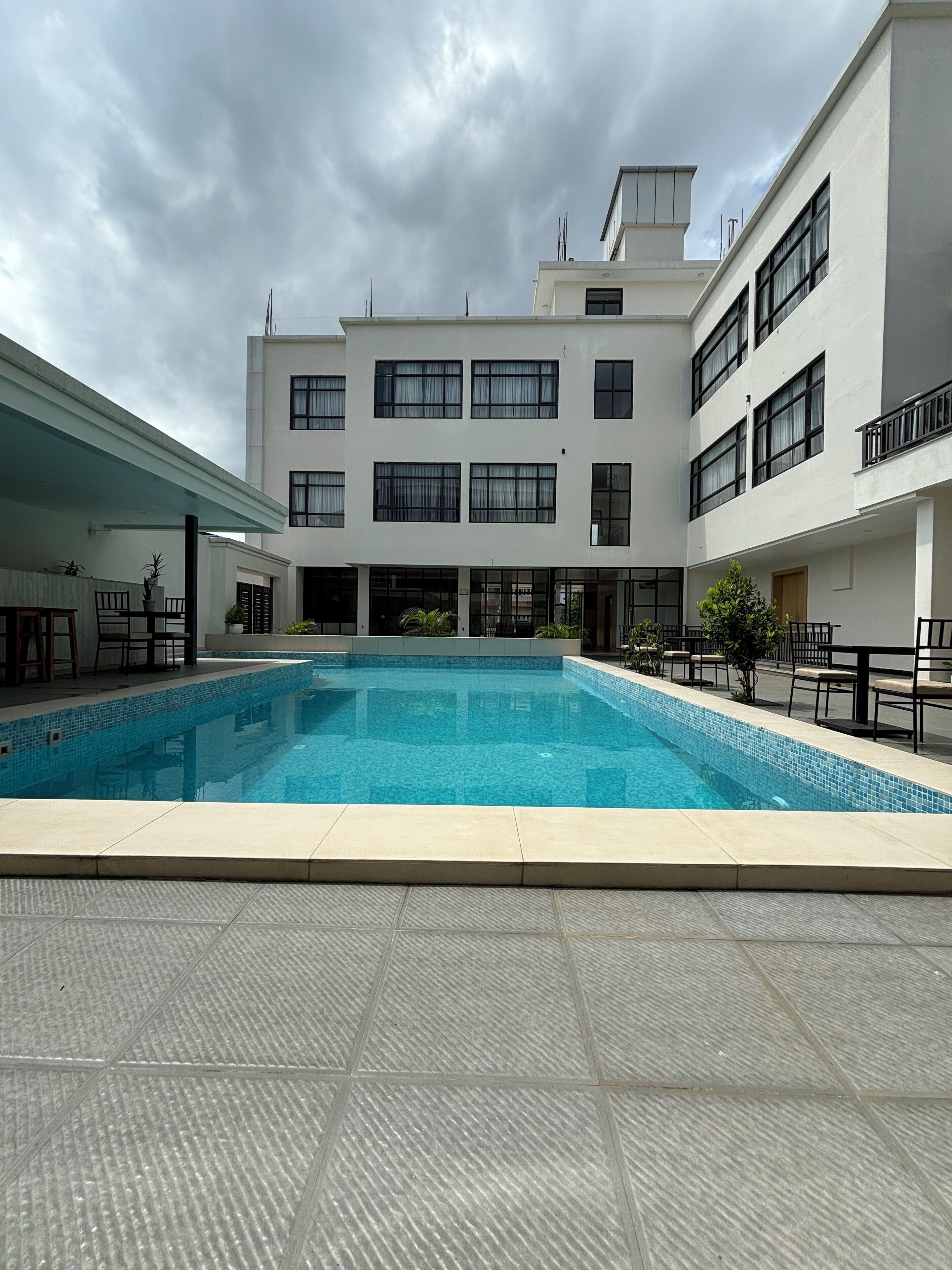 A modern building with a swimming pool, multiple balconies, and outdoor seating areas.