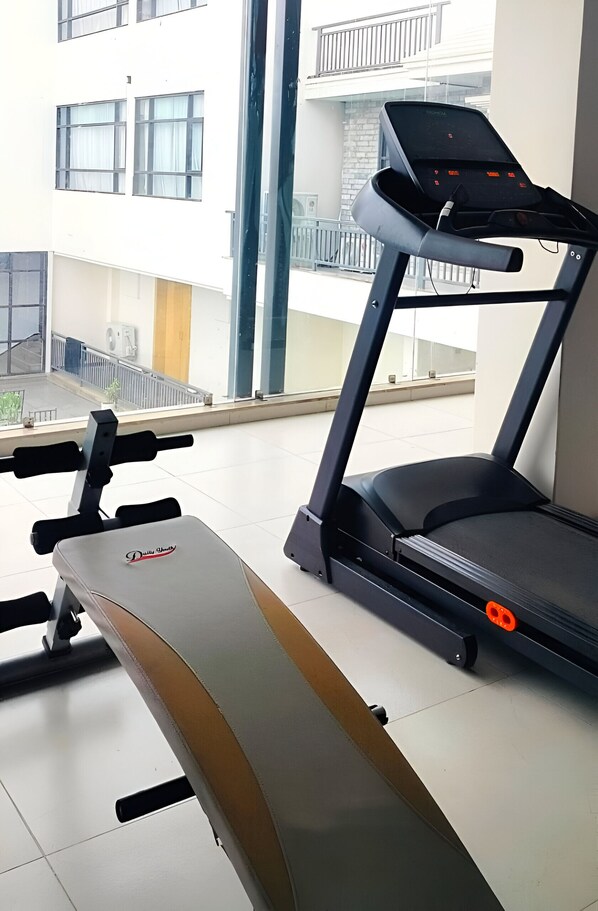 Un gimnasio con una cinta de correr y un banco.