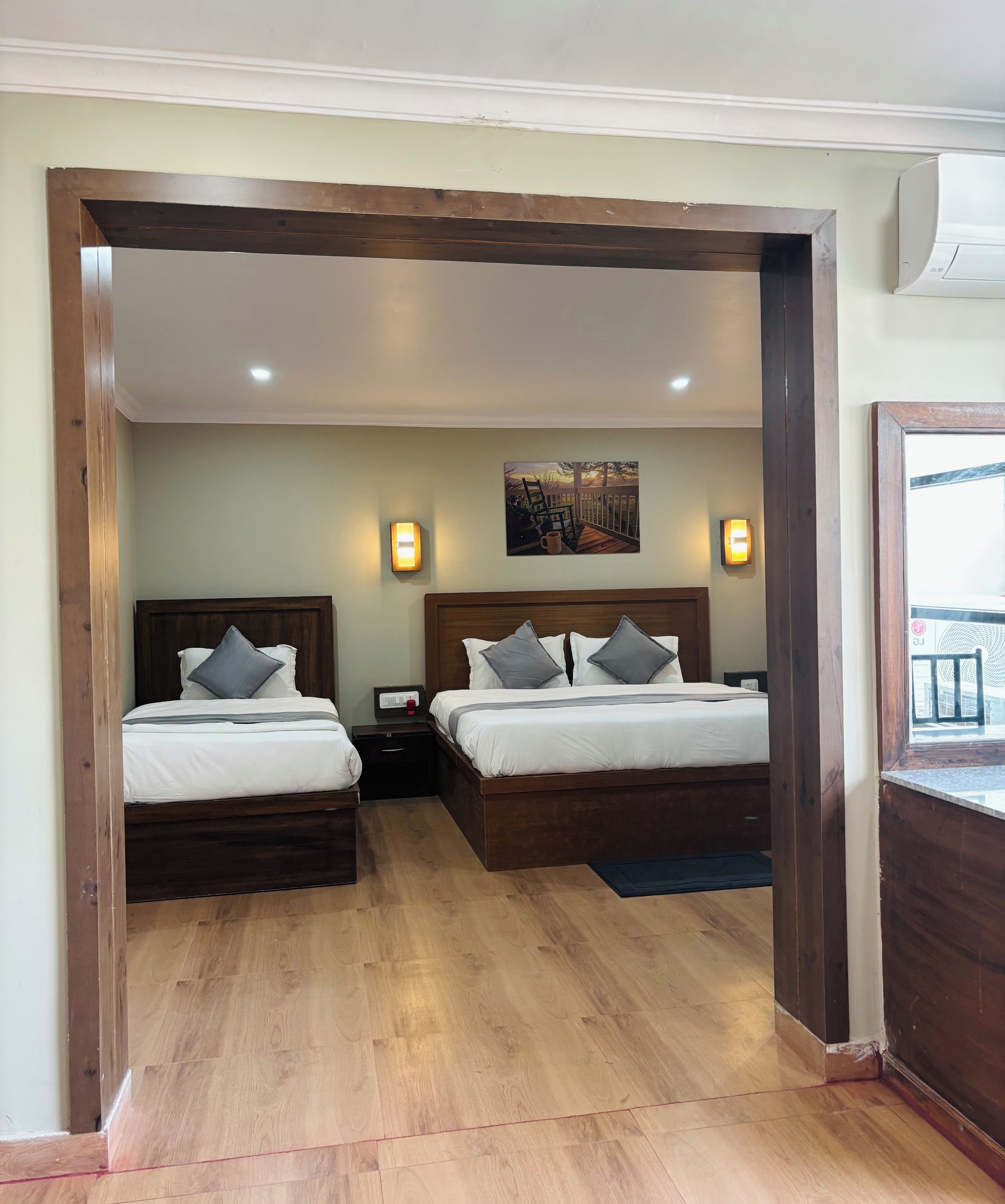 A hotel room with two beds, a painting on the wall, and a view of the outside.