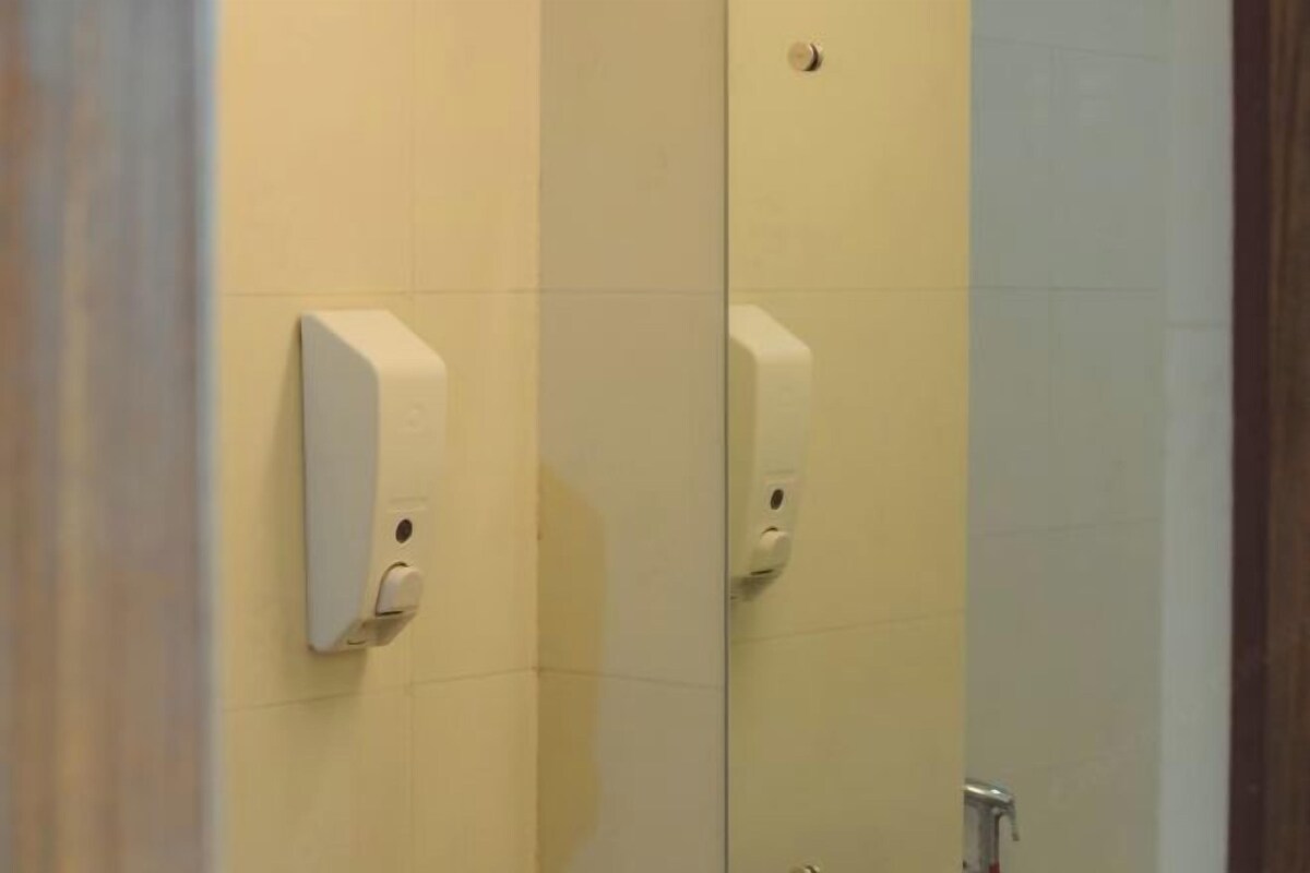 A restroom with a hand sanitizer dispenser mounted on the wall.