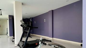 Un gimnasio con cinta de correr, banco de pesas y diversos equipos de ejercicio.