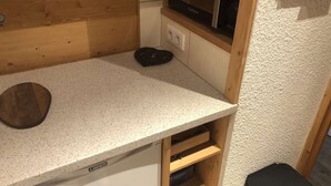 Una kitchenette con microondas, una encimera de madera y un pequeño archivador.