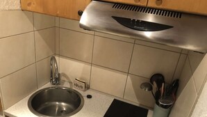 Una cocina con un lavamanos de acero inoxidable, un tostador y una placa de inducción negra.