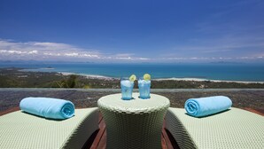A view from a balcony with a table, two towels, and two glasses of a blue beverage with lemon slices.