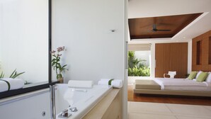 A modern bathroom with a large bathtub, a mirror, and a potted plant.