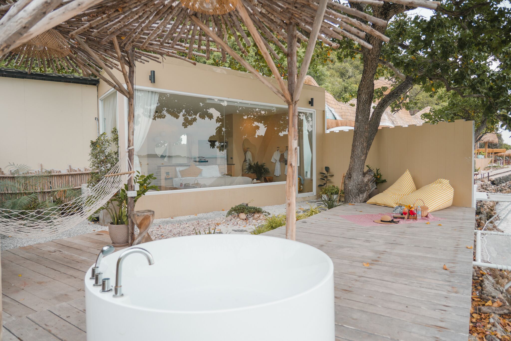 A spa area with a large bathtub, a wooden deck, and a glass-enclosed room with a view.
