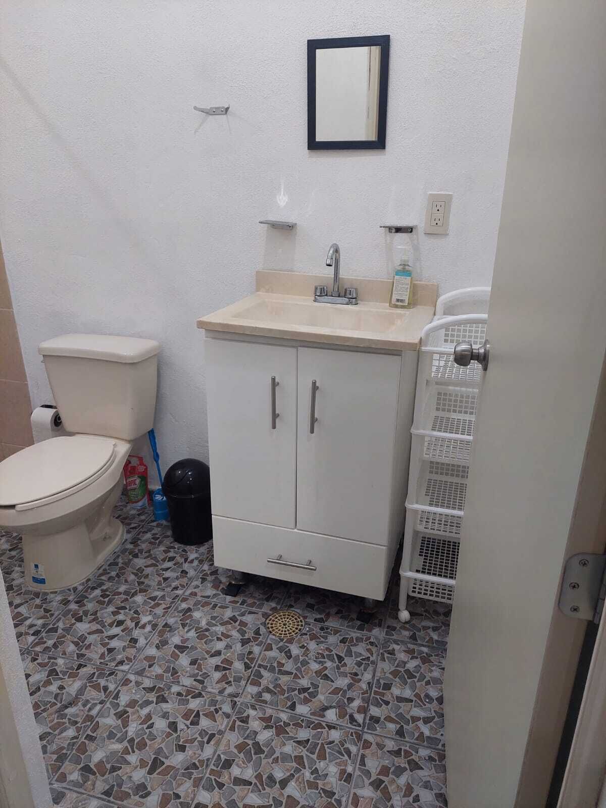 A small bathroom with a toilet, sink, and cabinet.